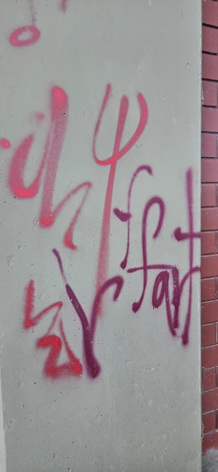 Graffiti spray paint on concrete wall before removal