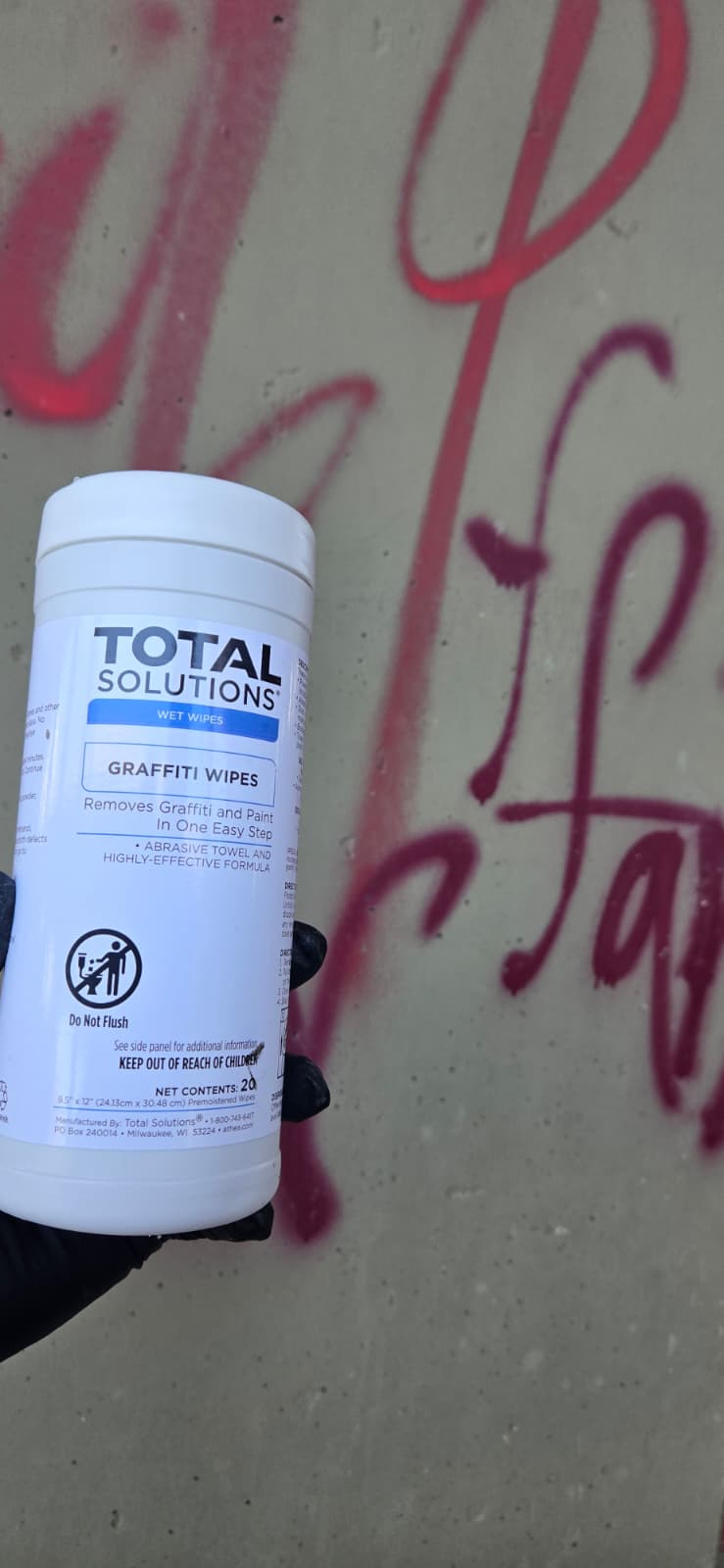 Total Solutions GraffitiWipe wipes canister held up in front of graffiti wall