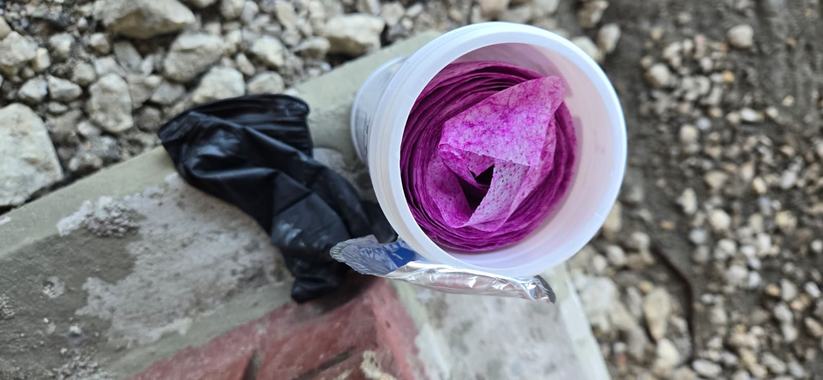 Open canister of purple-stained GraffitiWipe wipes after removing graffiti