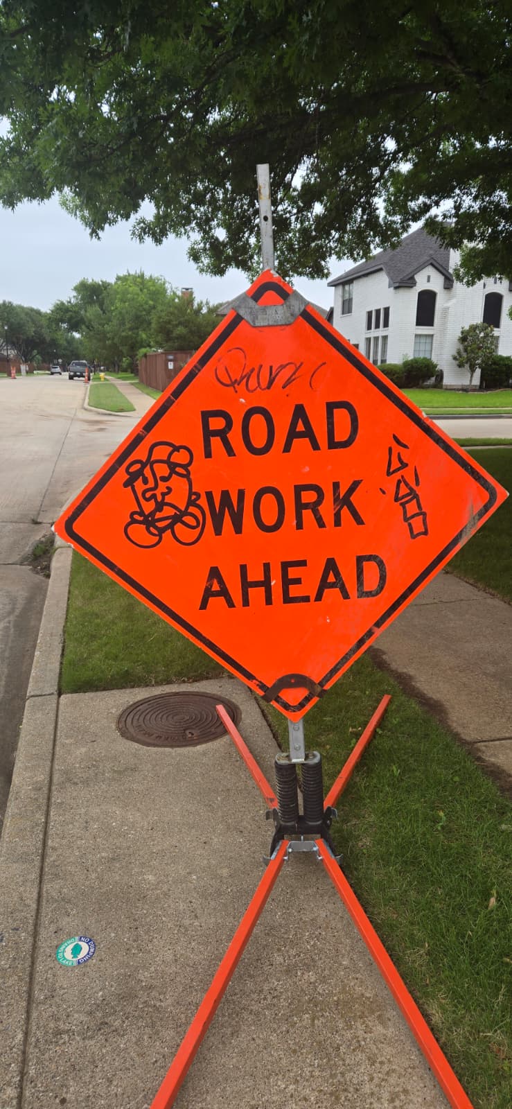 Graffiti vandalism tagged on road work ahead construction sign